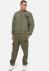 Olivegrøn quiltet bomberjakke med sort logo, lynlås-lukning og manchetter i kanten. Sammen med matchende cargo sweatpants med en sidelomme.