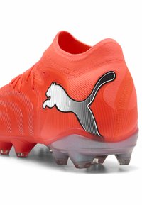 Kirkkaan oranssi jalkapallokengän yläosa on teksturoitu, pohjassa on nastat ja kantapäässä mustavalkoinen Puma-logo.