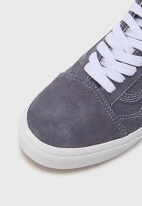 Hallid seemisnahast vabaajajalanõud valgete paeltega, ümarate varvastega, tekstuurse pinnaga ja kontrastse õmblusega külgedel.