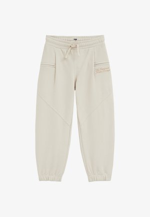 Pantalon beige décontracté avec taille et poignets élastiques, cordon de serrage, poches latérales zippées et texte brodé subtil sur la partie supérieure de la jambe droite.