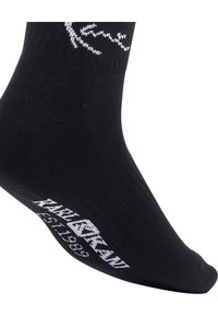 Fekete pamut zokni, fehér logóval a szárán, valamint "KARL LAGERFELD EST. 1984" felirattal az oldalon. Sima textúra, közép-vádli hosszúság.