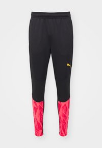 Zwarte atletische broek met een gemeleerde afwerking, voorzien van roze geometrische patronen op de onderbenen en een gele logo aan de zijkant.