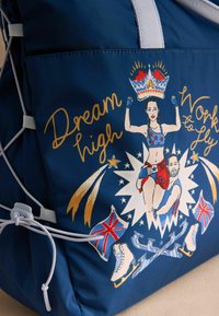 Námorn�ícky látkový batoh s ilustráciou dvoch postáv, hviezd a britských vlajok. Obsahuje biely hardvér a nastaviteľné popruhy.