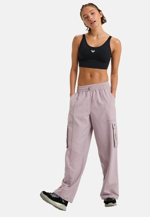Soutien-gorge de sport noir et pantalon cargo rose clair avec poches latérales. Les pantalons ont une coupe décontractée et une taille élastique, avec des accents de couture contrastants.