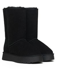 Botas de tobillo de ante negro con punta redondeada, forro interior suave y suela gruesa de goma negra. Detalles de costura a lo largo de la parte superior.