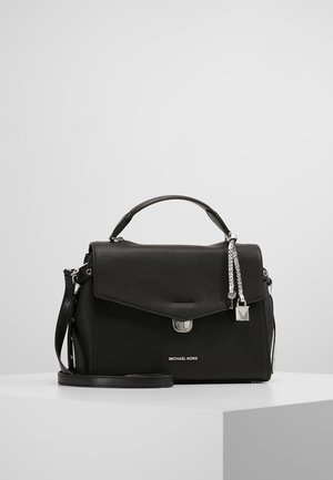 Czarna torebka Michael Kors z teksturowanej skóry, z uchwytem od góry, klapą zapinaną na zatrzask, srebrnym zamkiem oraz odpinanym paskiem na ramię, na białym tle.