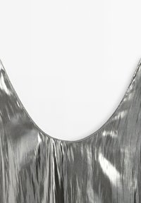 Silver metallic ärmlös topp med djup urringning, som har en mjuk, glänsande textur och vertikala ränder för extra detalj.