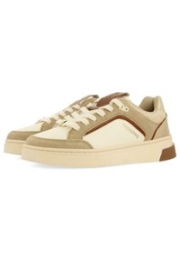 Zapatillas en beige y crema que presentan una combinación de materiales de ante y cuero, con acentos marrones y una suela texturizada. Ojal ovalado y cordones planos.