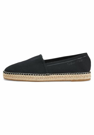 Espadrille noire sans lacets avec semelle en jute tissée et logo Calvin Klein sur le côté, vue de profil sur fond blanc.