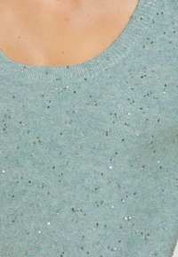 Lichtblauwe trui met een ronde halslijn en metallic pailletten die door de gestructureerde stof zijn verspreid. Zacht gebreid materiaal.