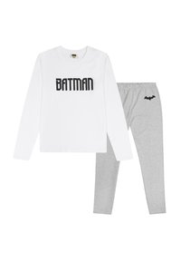 Langärmliges weißes Hemd mit "BATMAN" in schwarzem Text, kombiniert mit grauen Leggings, die ein kleines schwarzes Fledermaus-Logo an der Hüfte haben.