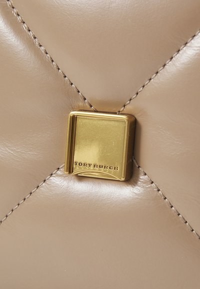 Geantă de mână din piele bej cu textură matlasată, având un închizător pătrat auriu cu "TORY BURCH" gravat. Cusături vizibile într-o culoare contrastantă.