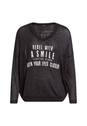 Black, loose-fitting sweater with a v-neckline and long sleeves. Features white text that reads “REBEL WITH A SMILE FLOATING ALONG WITH YOUR EYES CLOSED.”