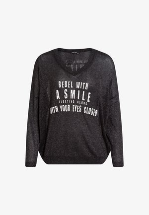 Black, loose-fitting sweater with a v-neckline and long sleeves. Features white text that reads “REBEL WITH A SMILE FLOATING ALONG WITH YOUR EYES CLOSED.”