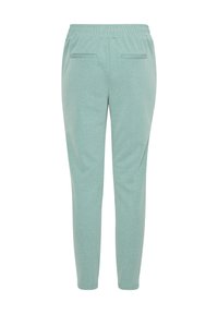 Pantalones de chándal de color verde claro, elásticos y con una textura suave, cinturilla elástica y dos bolsillos traseros. Diseño de pierna ajustada.