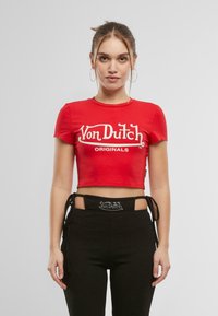 Červené bavlněné krátké tričko s bílým logem "Von Dutch Originals". Kombinováno s černými kalhotami s výřezovým designem a vázáním v pase.