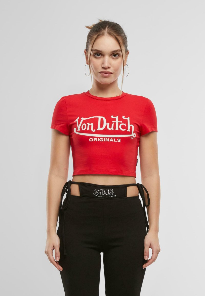 Červené bavlněné krátké tričko s bílým logem "Von Dutch Originals". Kombinováno s černými kalhotami s výřezovým designem a vázáním v pase.