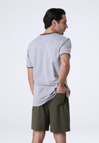T-shirt grigio a maniche corte con colletto verde oliva, abbinato a pantaloni corti verde oliva. Fit casual, tessuto morbido e tasche laterali.