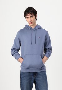 Felpa con cappuccio in azzurro chiaro. Presenta una tasca frontale, polsini e orlo a coste. Piccolo logo sul petto. Materiale in misto cotone.