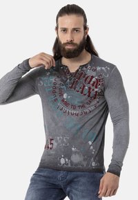 Langärmliges graues T-Shirt mit grafischen Mustern in Rot und Türkis, featuring einen Henley-Ausschnitt und einer strukturierten Oberfläche.