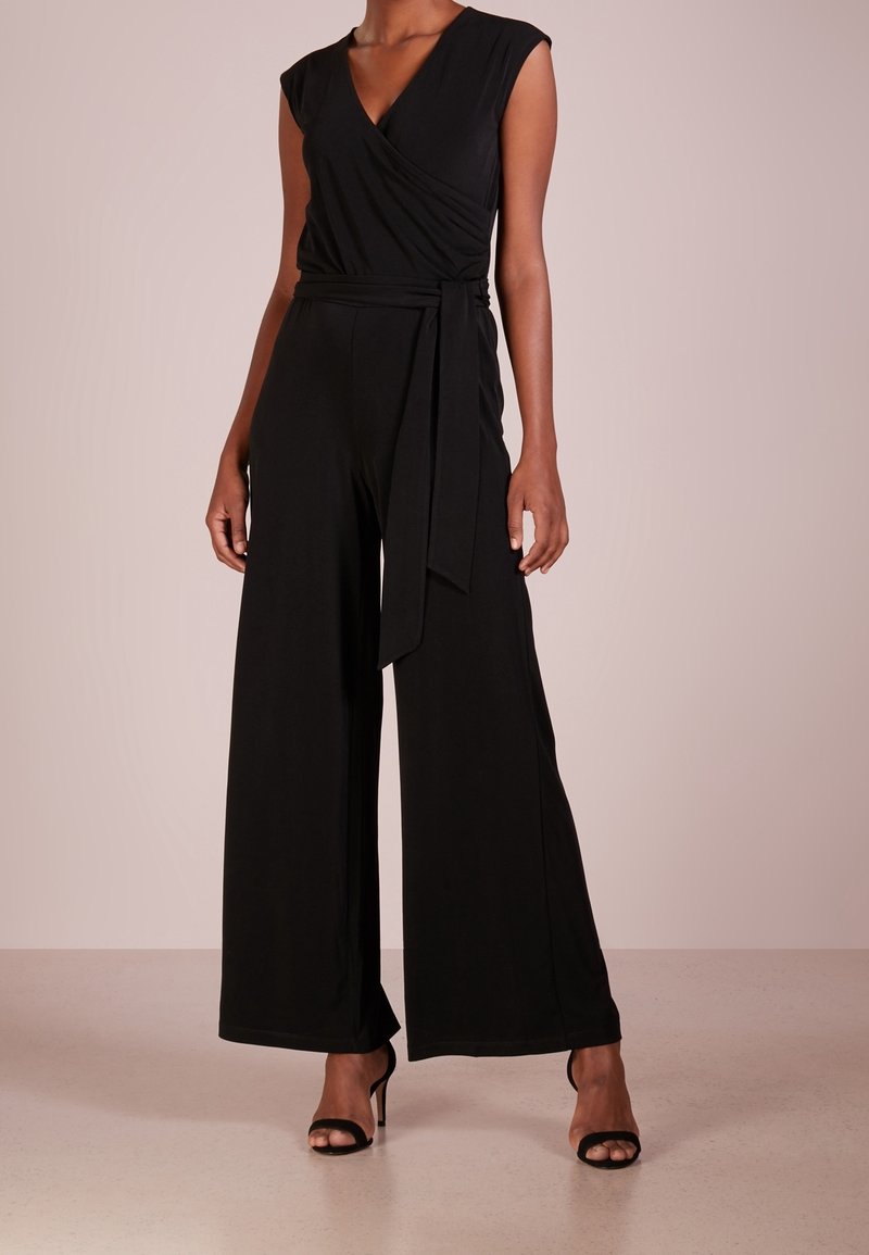 Svart jumpsuit med wrap-stil bodice, korta ärmar och vida ben. Tillverkad av mjukt tyg med en knytning i midjan.