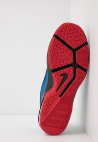 Rode rubberen zool met geometrisch profiel; zwarte accenten aan de zijkant en een blauwe bovenzijde. Beschikt over een logodetail aan de zijkant.