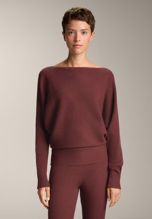 Bordeaux ribbelgebreide trui met een bootnek en een aansluitende zoom, gecombineerd met bijpassende ribbel leggings. Zachte textuur en een relaxte pasvorm.