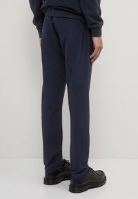 Pantaloni navy con vestibilità dritta, realizzati in tessuto morbido, dotati di cintura, tasche laterali e dettagli posteriori discreti.