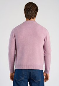 Vaaleanpunainen neulottu villapaita, jossa pyöreä pääntie, resorit hihansuissa ja helmassa. Materiaali on pehmeä ja hieman pörröinen, kuvattu takaa.