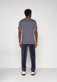 Γκρι κοντομάνικο T-shirt συνδυασμένο με ναυτικές παντελόνες. Οι παντελόνες έχουν απαλή υφή και λεπτομέρειες με πλευρική ρίγα. Μαύρα και λευκά αθλητικά παπούτσια.