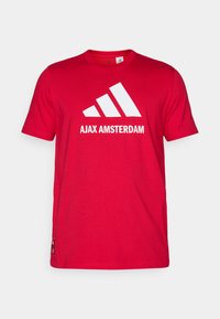 Rød bomulds T-shirt med et hvidt Adidas-logo og teksten "AJAX AMSTERDAM". Korte ærmer, rund hals, normal pasform.