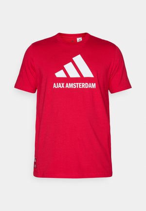 Červené bavlněné tričko s bílým logem Adidas a textem "AJAX AMSTERDAM". Krátké rukávy, kulatý výstřih, standardní střih.