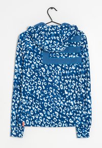 Blå fleecehuva med vitt leopardmönster, har en huva och en bakficka med tre horisontella ränder i en solid blå färg.