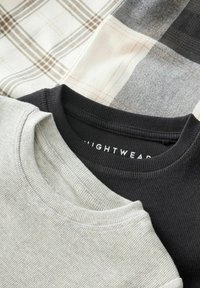 Tre camicie impilate, caratterizzate da una texture a coste grigio chiaro, un colletto nero solido e un tessuto a quadri in tonalità beige e grigio.
