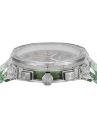 Τετράγωνο ρολόι με διάφανο κάστρο και φωτεινότερο πράσινο λουράκι. Μαύρος κοντράς με πορτοκαλί λεπτομέρειες και τρία υποδείκτες. Συμπεριλαμβάνονται ασημένια κουμπιά.