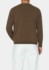 Maglione girocollo in lana marrone con una vestibilità rilassata, maniche e orlo a coste, abbinato a pantaloni in denim bianchi, viste posteriori.