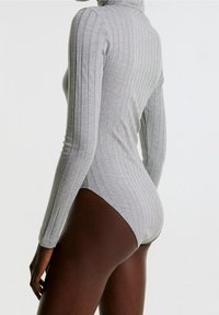 Grau geripptes Bodysuit mit hohem Kragen und langen Ärmeln, das eine figurbetonte Silhouette und ein nahtloses Design an den Hüften aufweist.