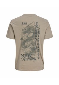 Μπεζ κοντομάνικη μπλούζα με λεπτομερή σκούρα εικόνα δράκου, ασιατικό στυλ γραφής και τις λέξεις "NEW Reality" τυπωμένες στην πλάτη.
