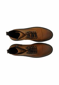 Bottes en cuir marron à cheville avec des lacets foncés, bout arrondi et semelles en caoutchouc noires. Le design présente une finition texturée et des coutures à l'avant.