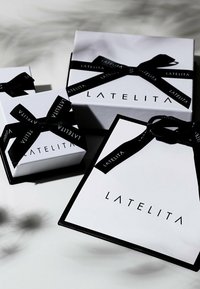 Tre presentlådor i vitt med svarta accenter, med varumärkesnamnet "LATELITA" i fet stil. Varje låda är prydd med ett svart band.