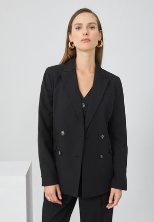 Blazer noir à double boutonnage avec revers en notch, boutons métalliques et coupe ajustée. Tissu lisse et silhouette droite.