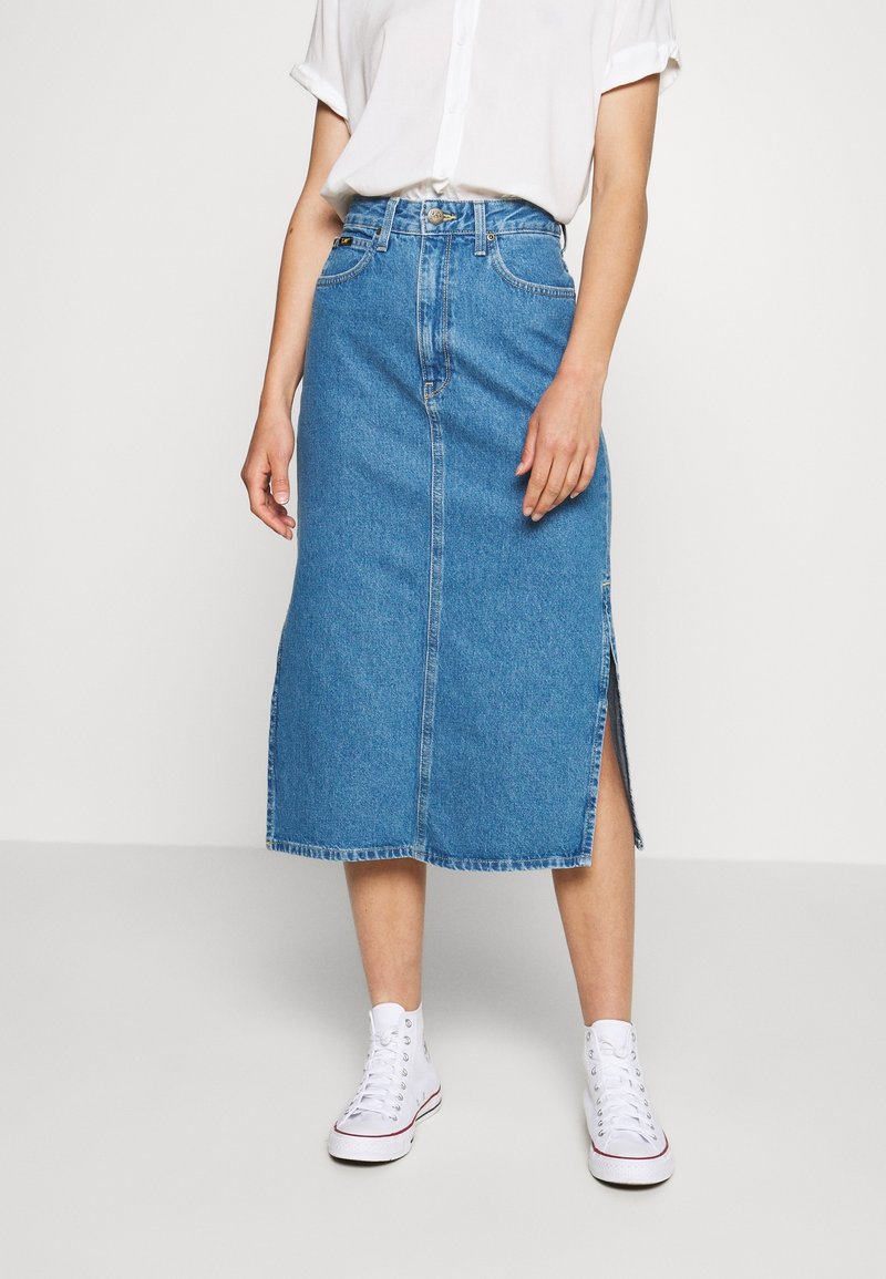 Vaaleansinisestä denimmidihameesta, jossa on suora leikkaus, sivuhalkio ja repsottavat reunat. Yhdistetty valkoisiin korkean nauhan tennareihin.