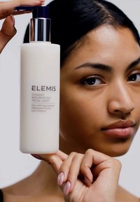 White bottle with a pump dispenser, labeled "ELEMI DYNAMIC RESURFACING FACIAL WASH" in purple text; smooth texture, sleek modern design.