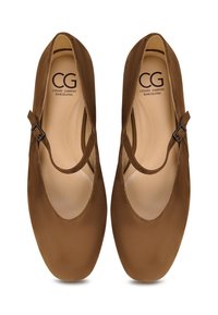 Zapatos Mary Jane de ante marrón con punta redondeada, diseño recortado y un pequeño detalle de hebilla en la correa. Forro interior suave.