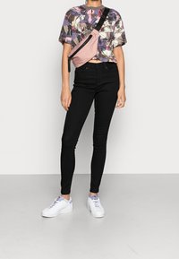 Top corto de algodón con un patrón floral multicolor, combinado con jeans ajustados negros y zapatillas blancas con acentos en lavanda.