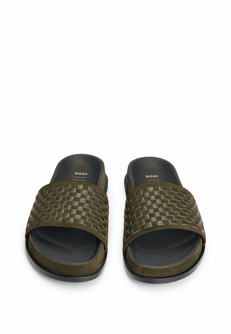 Zielone plecione klapki z tkaninowym paskiem o teksturowanej fakturze oraz gładką czarną gumową podeszwą, z delikatnym logo marki na wkładce.