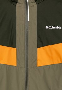 Jacheta verde și portocalie cu fermoar are un design colorat, o textură netedă și un logo Columbia pe piept, având un fermoar contrastant.