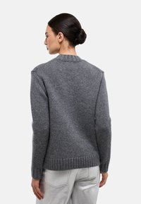 Pull en maille grise avec un col et des poignets côtelés, présentant une finition texturée. Vue de dos montrant la silhouette et les détails de la confection.