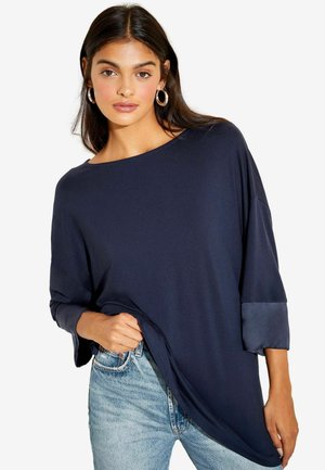 Navyblaues Übergrößenshirt mit Rundhalsausschnitt und Dreiviertelärmeln. Glatte Textur mit kontrastierenden Satinärmelakzenten.