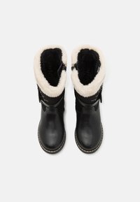Bottes noires imperméables avec un col en fourrure douce crème et noire, matériau extérieur lisse et une boucle décorative sur le côté.